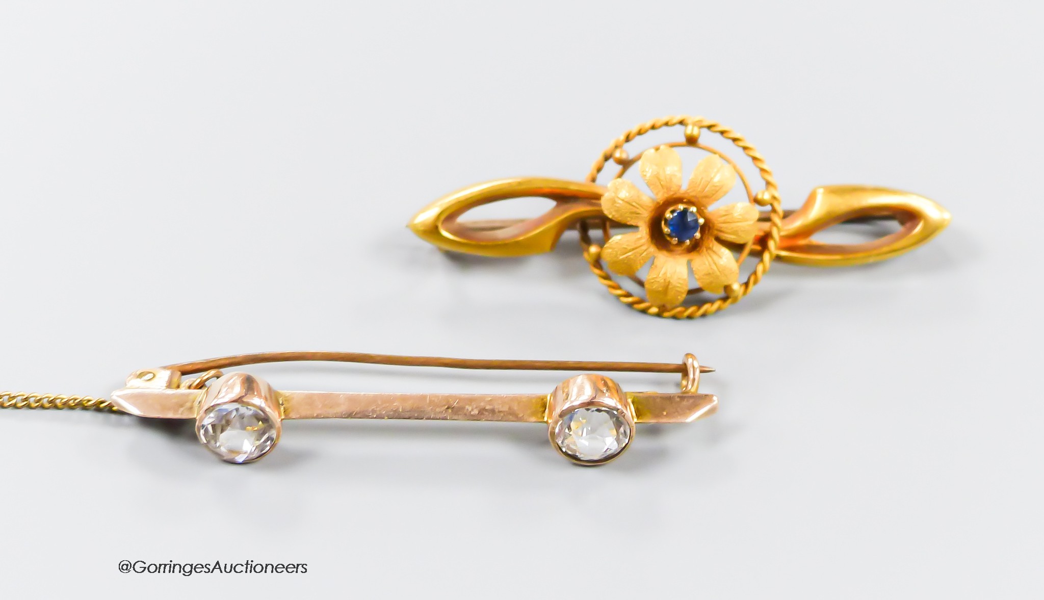 An Edwardian 15ct gold and sapphire set flower head bar brooch, 41mm, gross 2.6 grams and a 9ct and two stone paste set bar brooch, gross 2.6 grams.